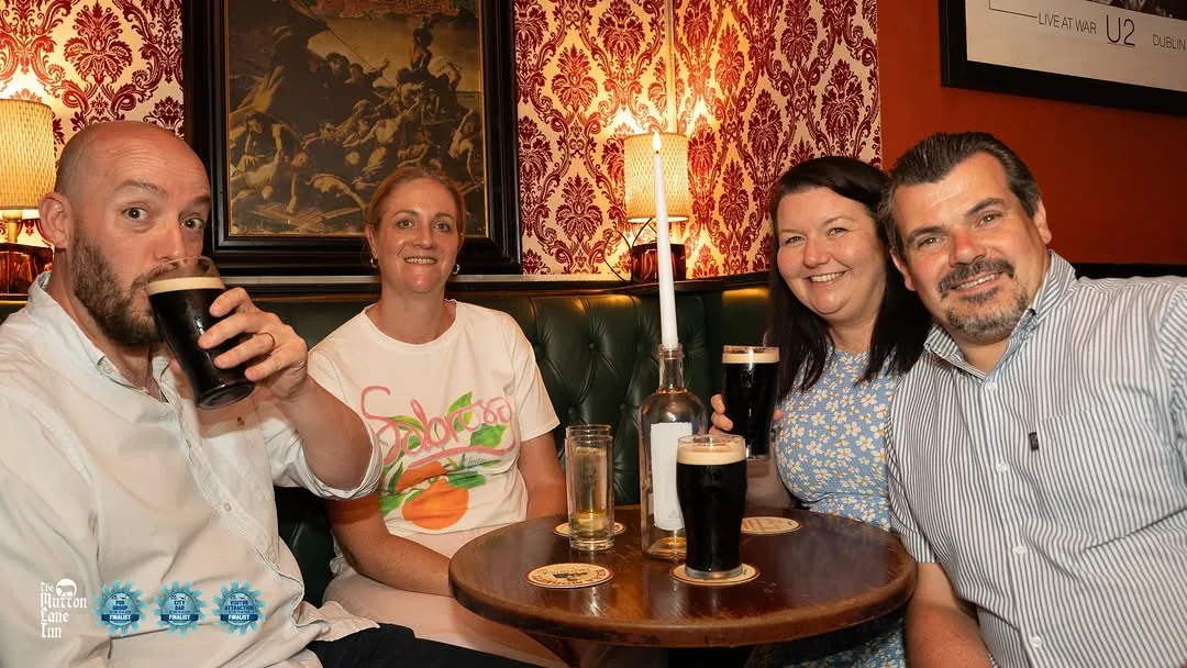 A group of friends sharing stout at a wooden table inside the pub