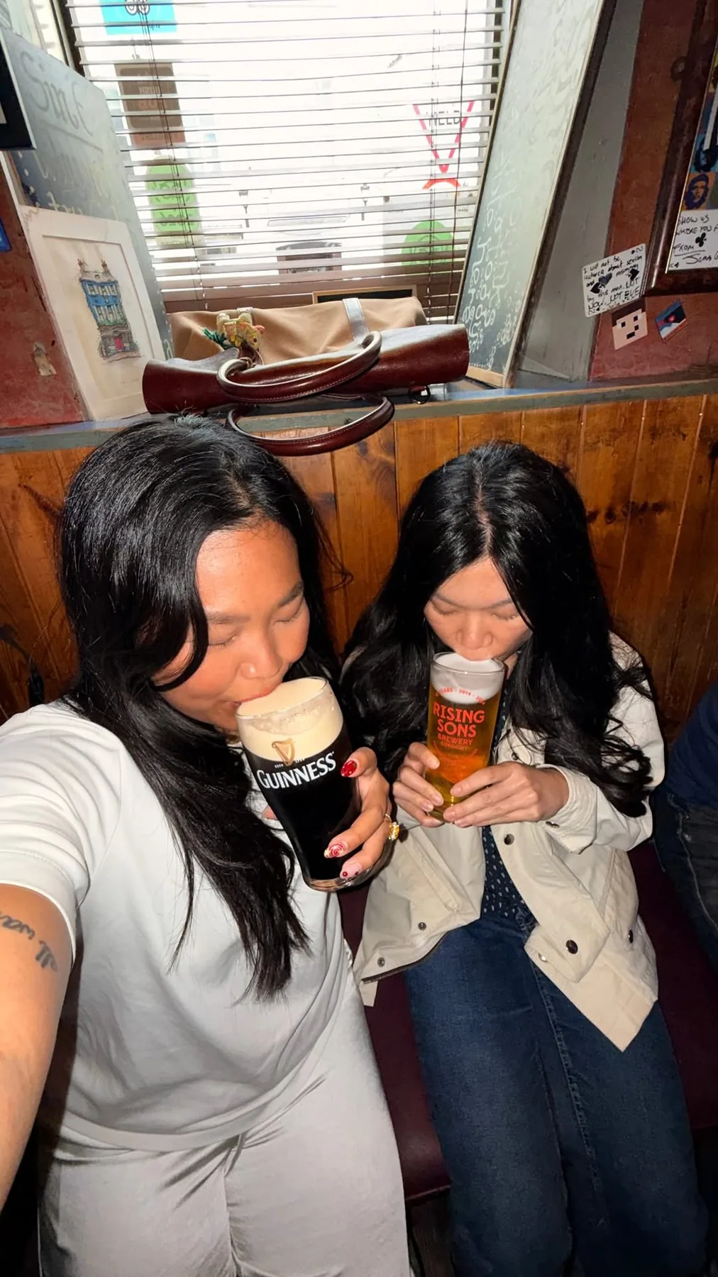 Two visitors enjoying Guinness and a local beer inside the pub